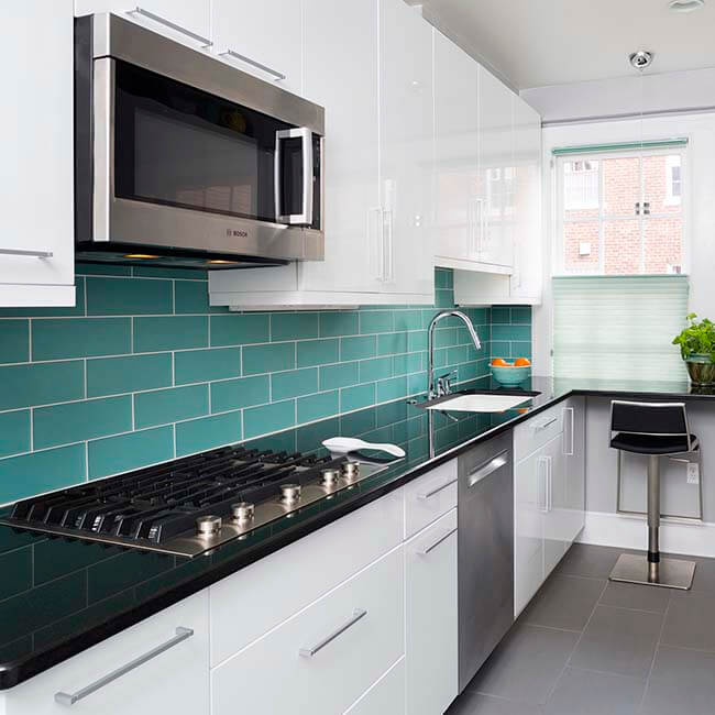 galley kitchen with Teal tile, white cabinets, stainless steel appliences, and dark quartz counters Halifax Case Design